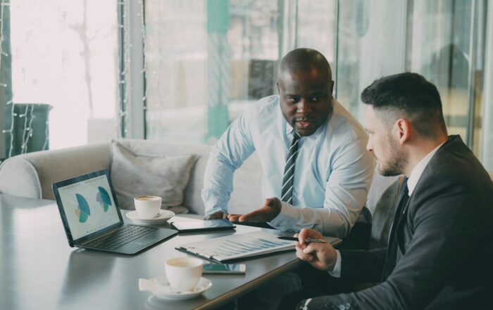 Two businessmen reviewing charts on a laptop at a conference table