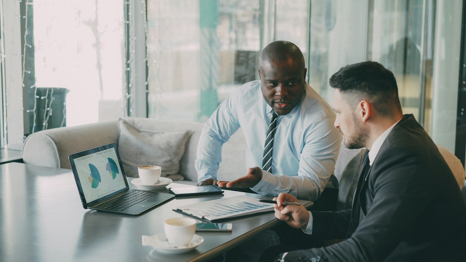 Two businessmen reviewing charts on a laptop at a conference table