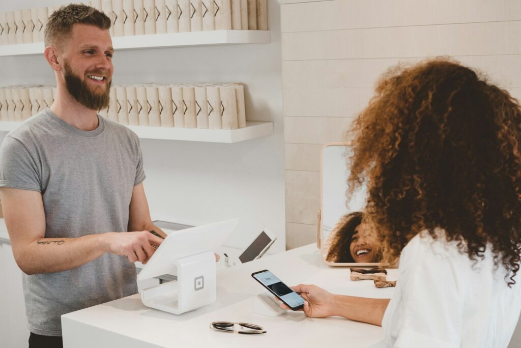 Smiling shop owner helping a customer at the checkout counter