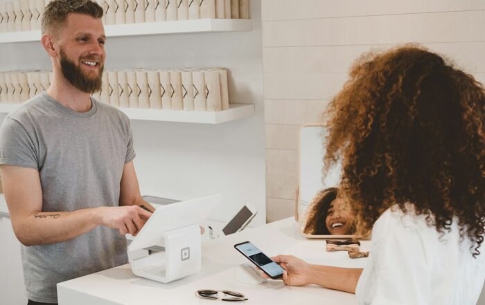 Smiling shop owner helping a customer at the checkout counter