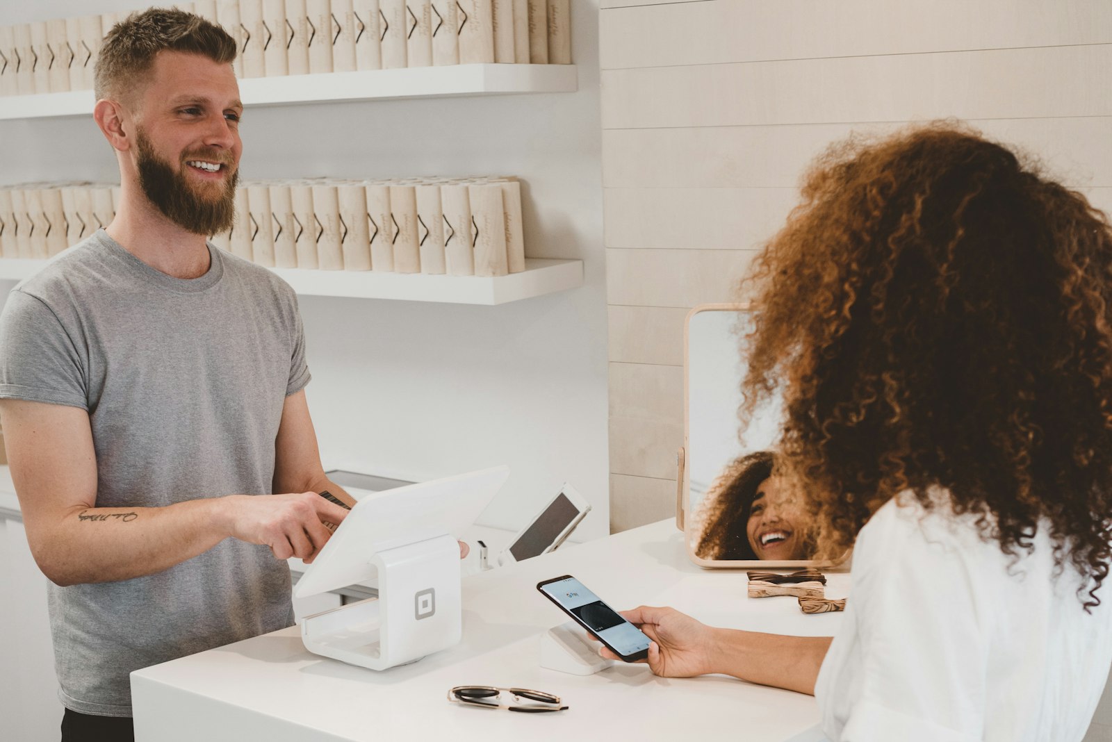 Smiling shop owner helping a customer at the checkout counter