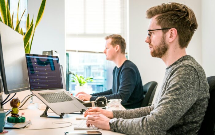 Two men working at computers in a bright office