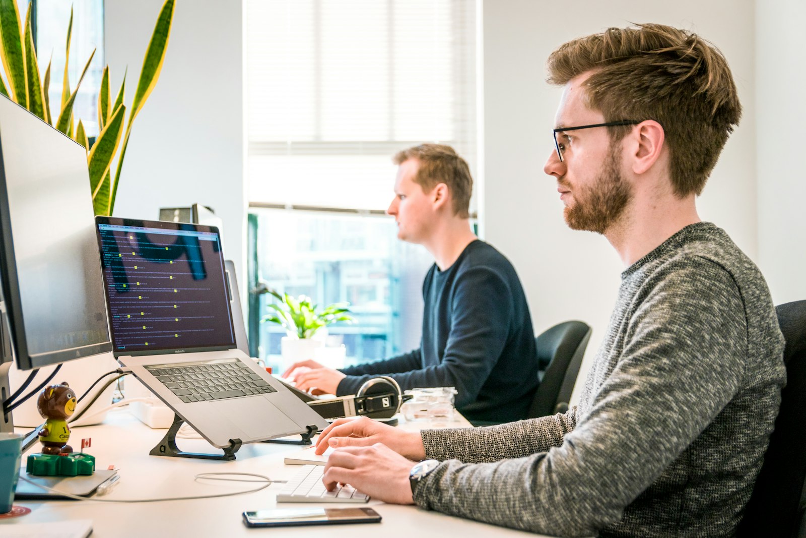 Two men working at computers in a bright office