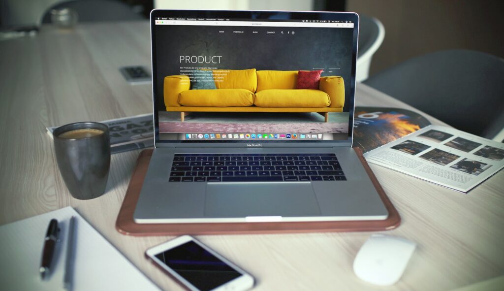 Laptop displaying an online store product page featuring a yellow sofa, next to a coffee mug