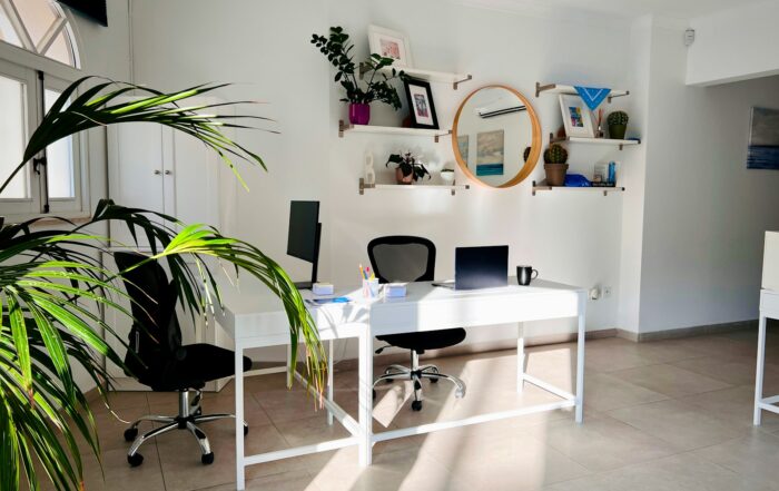 Bright, tidy office with a white desk, laptop and green plants