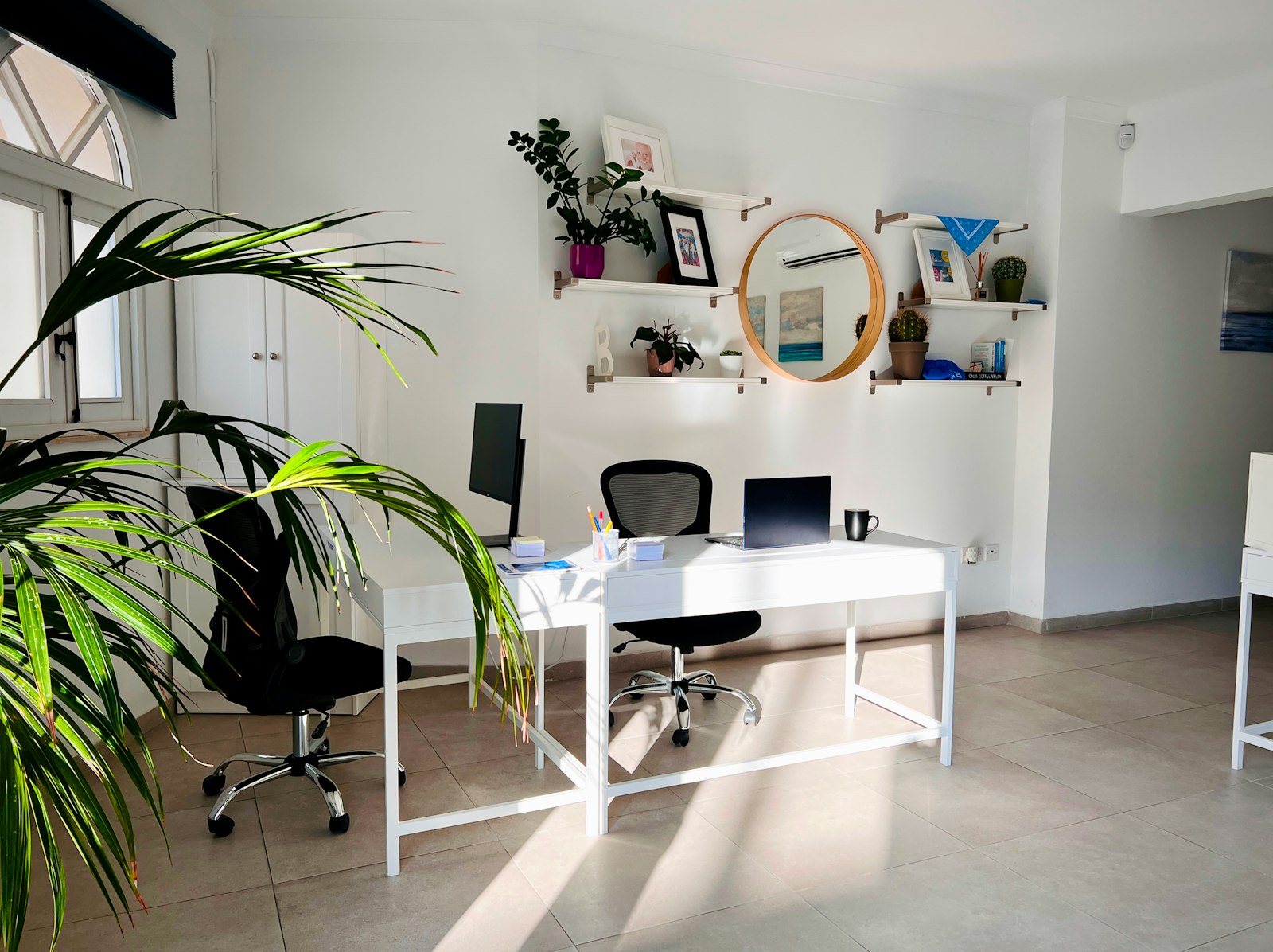 Bright, tidy office with a white desk, laptop and green plants
